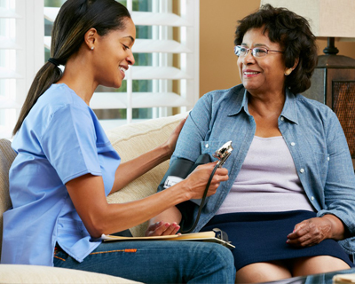 a caregiver checking the blood pressure of a senior woman